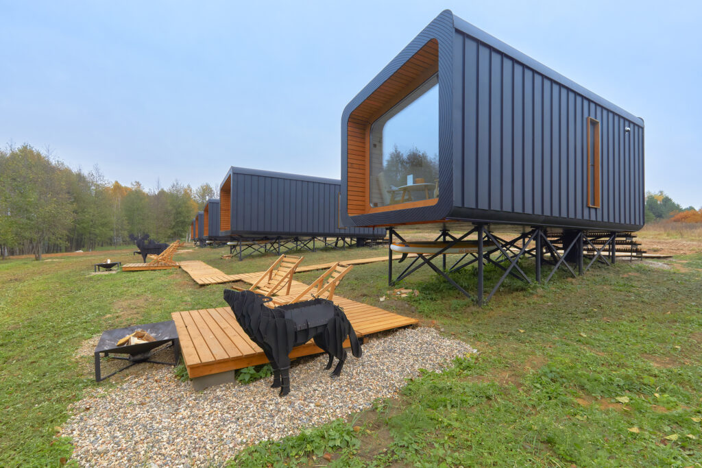 A group of BRO6 cabins connected by a boardwalk in a green landscape