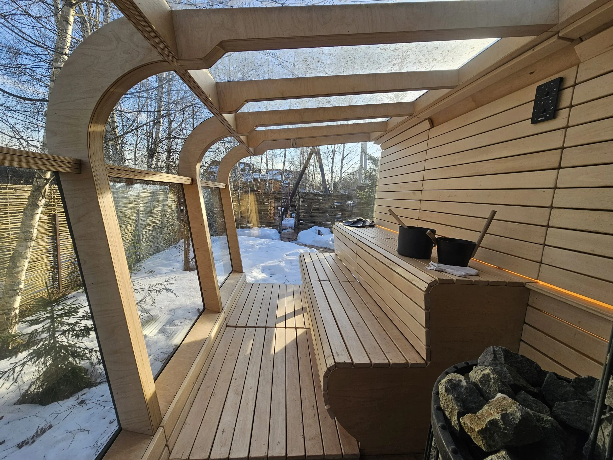 Wood-lined panoramic sauna interior with bench, glass wall and heater