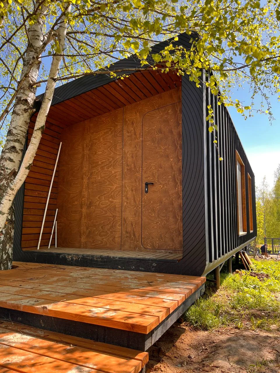 Timber landing and steps at the entrance of a dark-clad wooden cabin