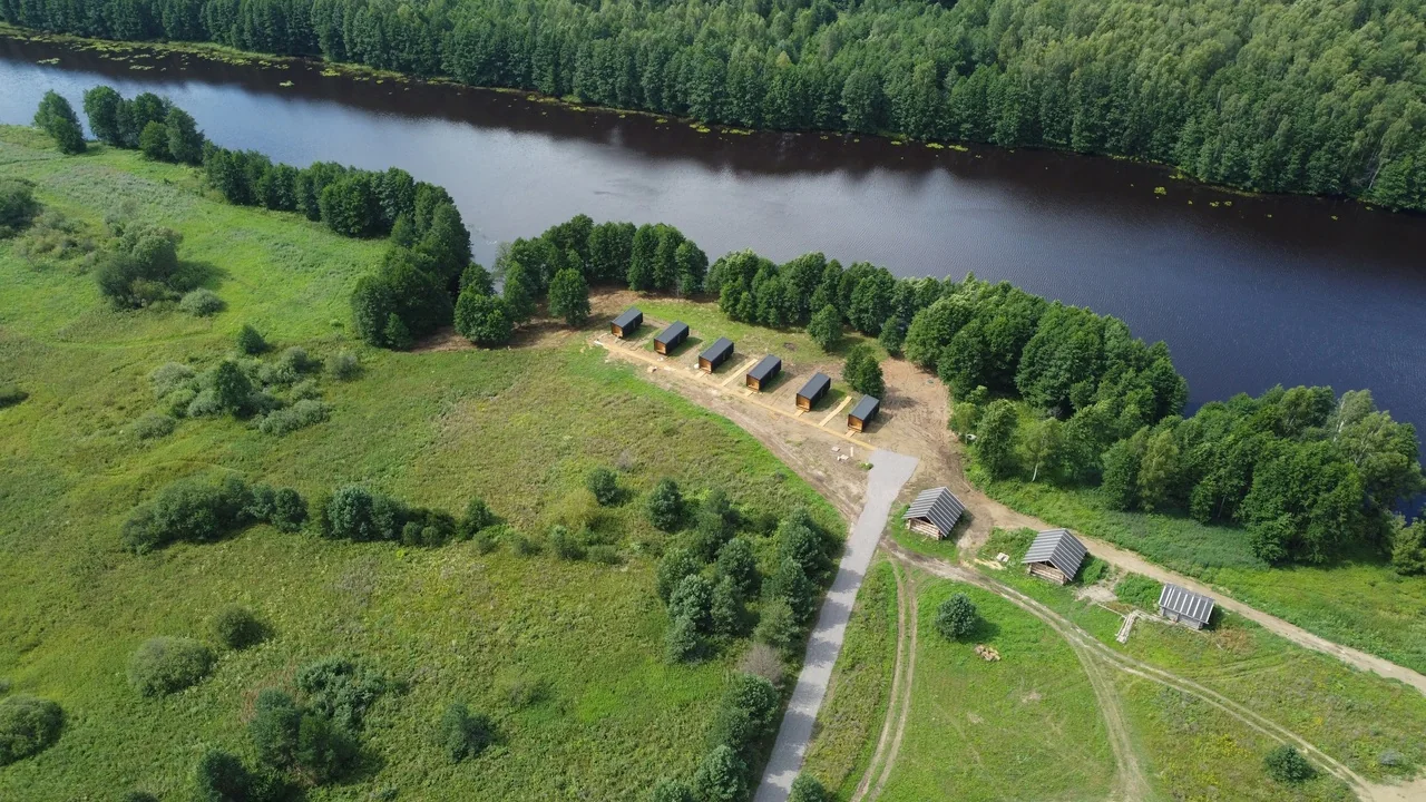 Aerial view of several small cabins arranged beside a lake and access path
